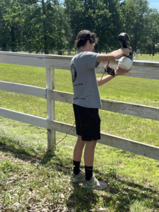 A handyman using a paint sprayer to paint a fence for S&S Handyman Services in Reno, NV