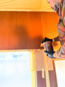 A handyman from Bespoke Finish staining wood paneling, protected by 3M film, in Minneapolis, MN.