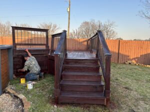 A handyman staining a wooden deck and pool surround for BK's Handyman Services in Carlton, OR.
