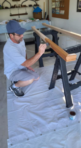 A handyman staining a wooden handrail, demonstrating a service by Small Jobs Well Done in Avon, CT.