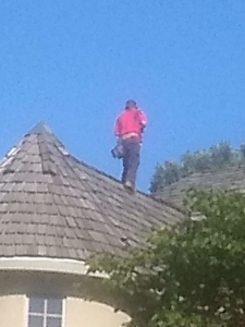 A handyman standing on a conical roof, performing work or inspection for Superior Roof Support in Milano, TX.