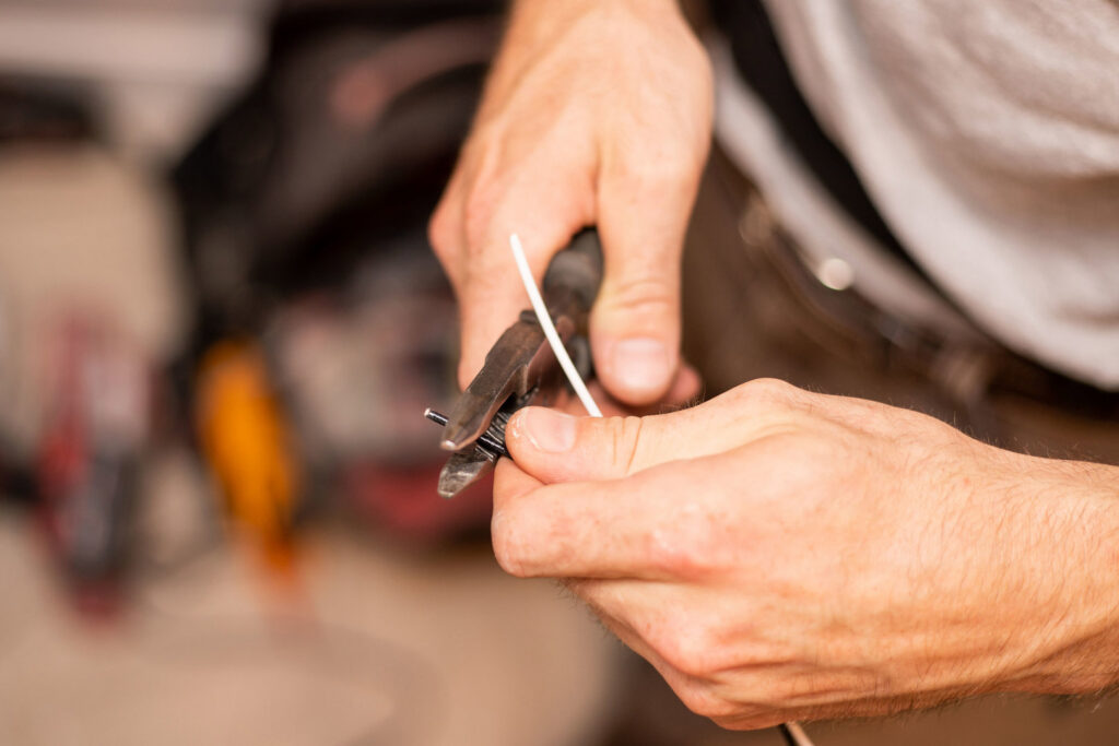 Close-up of a handyman's hands stripping an electrical wire with pliers for Paul Bergeron Jr. Contracting Inc. in Worcester, MA