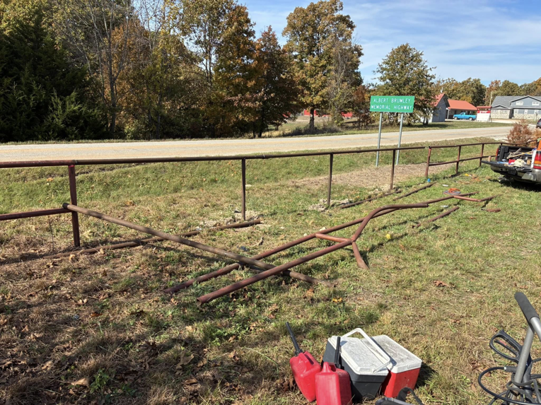 Handyman tools on the ground next to a metal fence being repaired by Wild Hogs Handyman Service in Bentonville, AR.