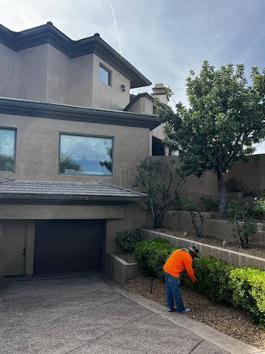 A handyman trimming bushes and performing landscaping services outside a home for Vegas Valley Remodeling/Handy-Man Services in Las Vegas, NV.