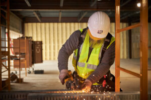 A handyman from EV Construction using an angle grinder, creating sparks, at a job site in Holland, MI.