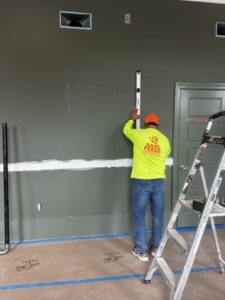 A handyman using a level to mark a wall for installation by Saul Perez Renovations LLC in Macon, GA.