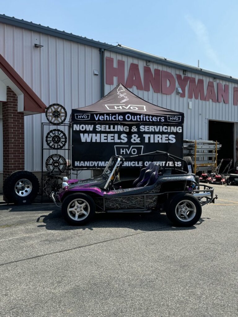 The storefront of Handyman Vehicle Outfitters featuring a custom dune buggy and service tent in Portland, ME.