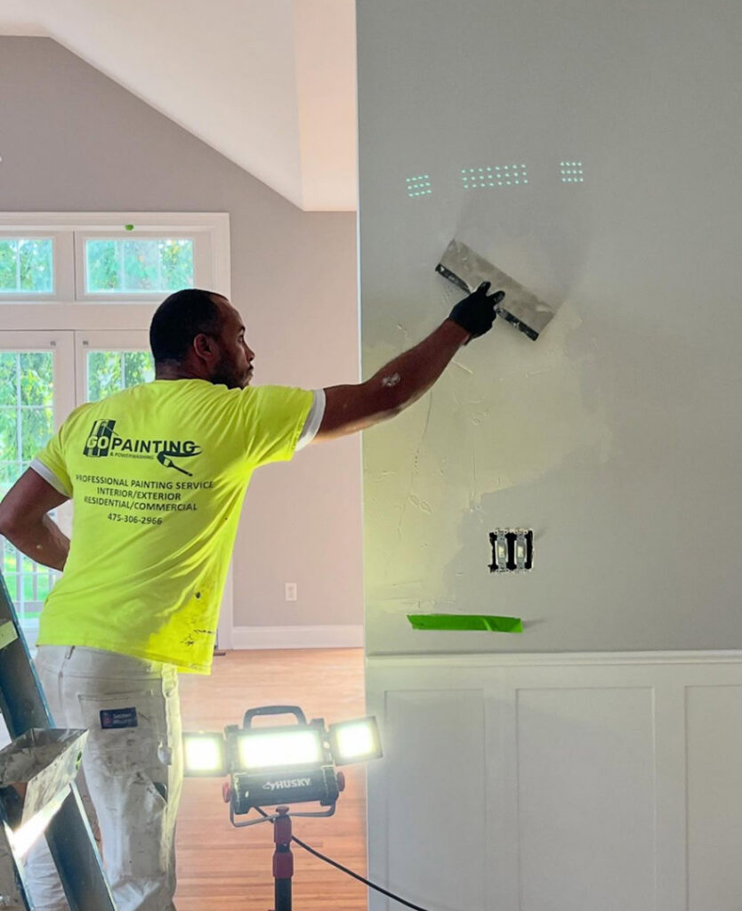 A handyman from GO Painting performing wall repair and plastering in New Haven, CT