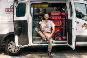 A handyman holding pliers, sitting in his organized work van filled with tools from Paul Bergeron Jr. Contracting Inc. in Worcester, MA