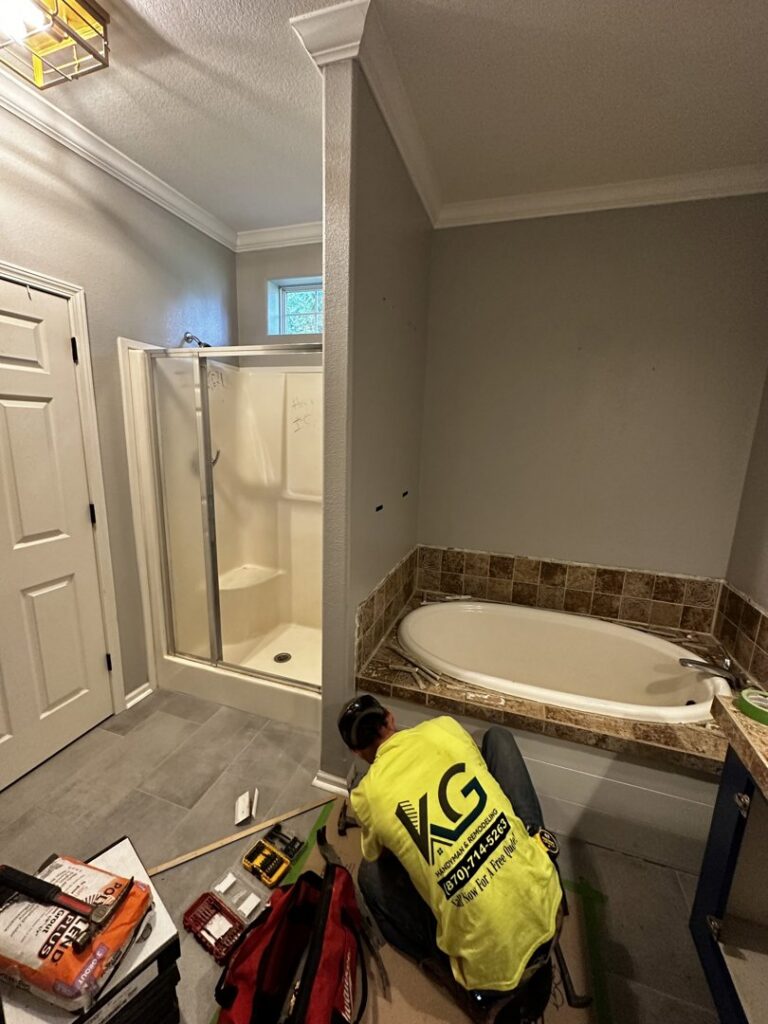 Handyman working on a bathroom remodel with new tub and shower enclosure by KG Handyman & Remodeling in Vilonia, AR.