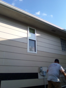 A handyman working on exterior siding and repairs on a house by Picasso Handyman Painters in Wichita, KS.