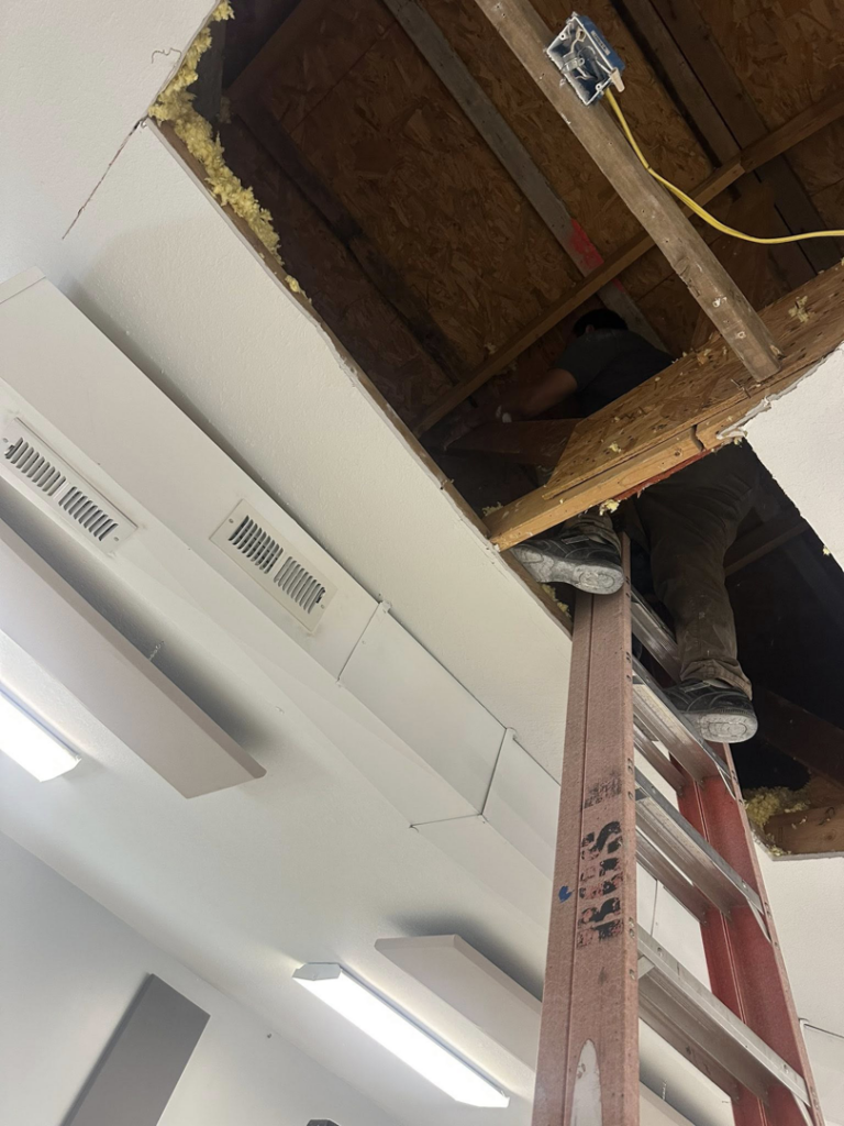 A handyman from Husky drywall LLC working on a ladder in an attic space in Kansas City, MO.