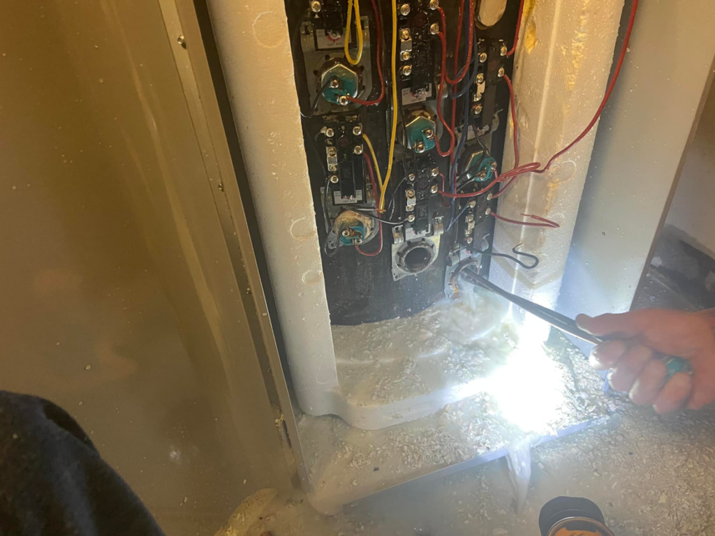 A handyman from Handyman Al working on an appliance repair, using a wrench on exposed components in Rapid City, SD.