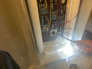 A handyman from Handyman Al working on an appliance repair, using a wrench on exposed components in Rapid City, SD.