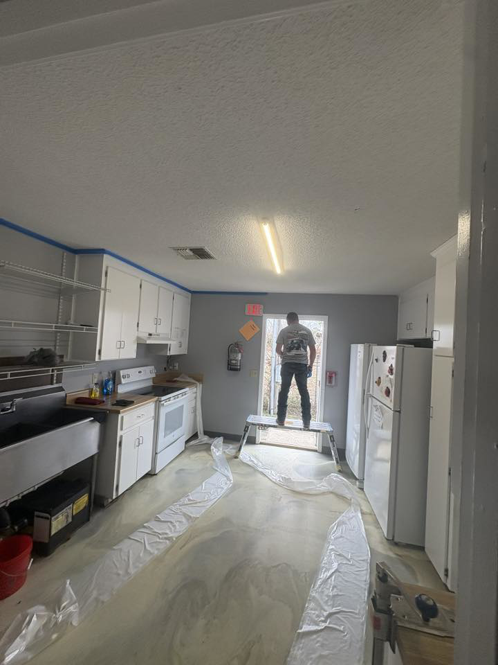 Handyman working on a kitchen ceiling with painter's tape and drop cloths by Diamond Drywall LLC in Buda, TX