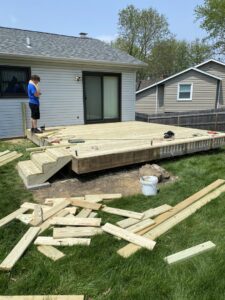 A handyman working on deck construction with lumber scattered on the grass, by Aaron's Handyman Service in Tucson, AZ.