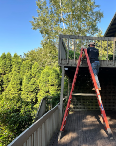 A handyman on a ladder working on a deck railing, providing renovation services for Rosas Construction and Renovation in Dallas, TX.
