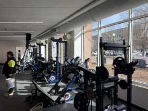 A handyman working on overhead ductwork or ceiling in a commercial gym by Jack Ellison Painting Contractors Inc. in Montgomery, AL.