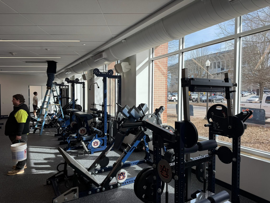 A handyman working on overhead ductwork or ceiling in a commercial gym by Jack Ellison Painting Contractors Inc. in Montgomery, AL.