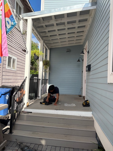 A handyman working on the porch floor of a house in New Orleans, LA, provided by Richard Earls Construction.