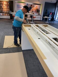 A handyman working on assembling or repairing a display table in a retail store for Vegas Valley Remodeling/Handy-Man Services in Las Vegas, NV.