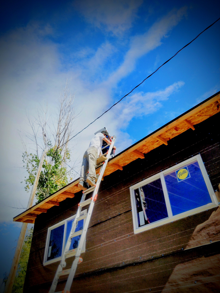 A handyman on a ladder working on roof eaves during construction by Investment Handyman Services in Pocatello, ID