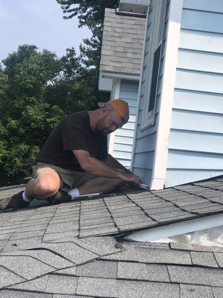 A handyman from Dream Construction working on roof and siding repair near a dormer in Johnson City, TN.