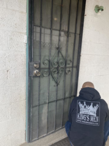 A King's Men handyman inspecting or repairing a security door in Las Cruces, NM.