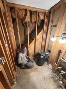 A handyman working on exposed wall framing during a renovation project by Urban Restoration, LLC in Indianapolis, IN