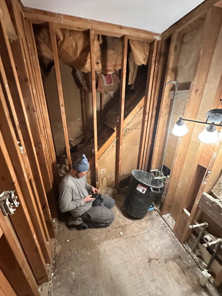 A handyman working on exposed wall framing during a renovation project by Urban Restoration, LLC in Indianapolis, IN