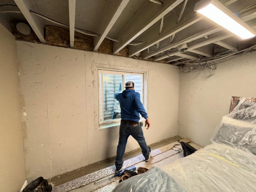 A handyman from iFloor working on a window during a basement renovation project in Westminster, CO.