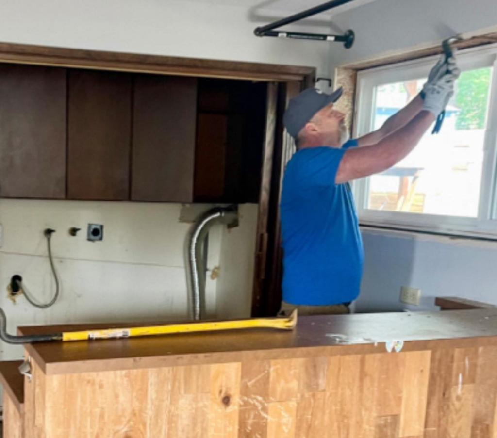 A handyman from Grace & Grit Remodeling LLC working on a window frame during a home renovation project in Vancouver, WA.