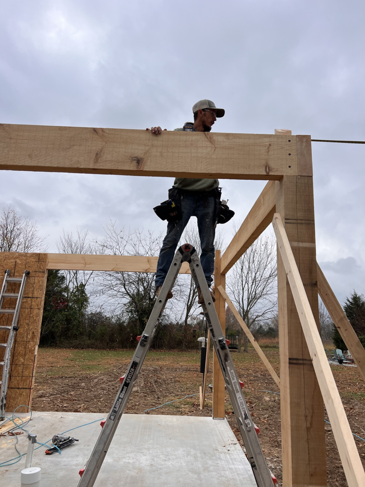 A handyman on a ladder installing wooden framing for a new structure by Classic Home Concepts in Springfield, MO