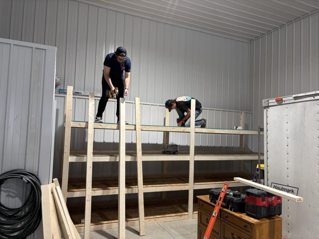 Two handymen from Dakota Small Jobs building custom wooden shelves in a garage in Sioux Falls, SD.