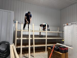 Two handymen from Dakota Small Jobs building custom wooden shelves in a garage in Sioux Falls, SD.