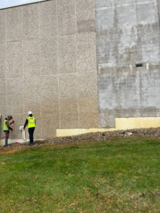 Two handymen performing exterior ground and wall maintenance for TRM Staffing LLC in Indianapolis, IN.