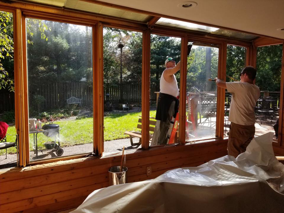 Two handymen installing new windows in a sunroom during a remodeling project by Gerlach Handyman in Eau Claire, WI.