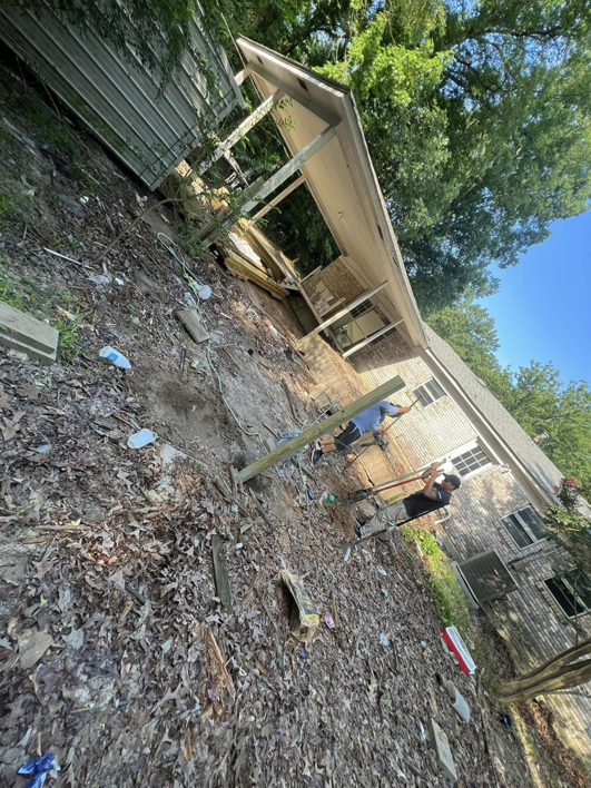 Two handymen installing a wooden deck post, demonstrating construction work by JD Handyman service LLC in Miami, FL.