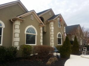 Handymen on ladders working on the exterior of a large house, possibly painting or repairing, by GCI Services, Inc. in Simpsonville, SC