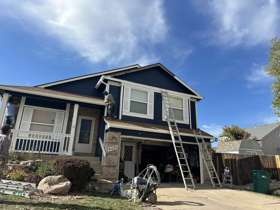 Handymen painting the exterior of a house with ladders and equipment for Froese's Creative Concepts & Luxury Designs LLC in Denver, CO.