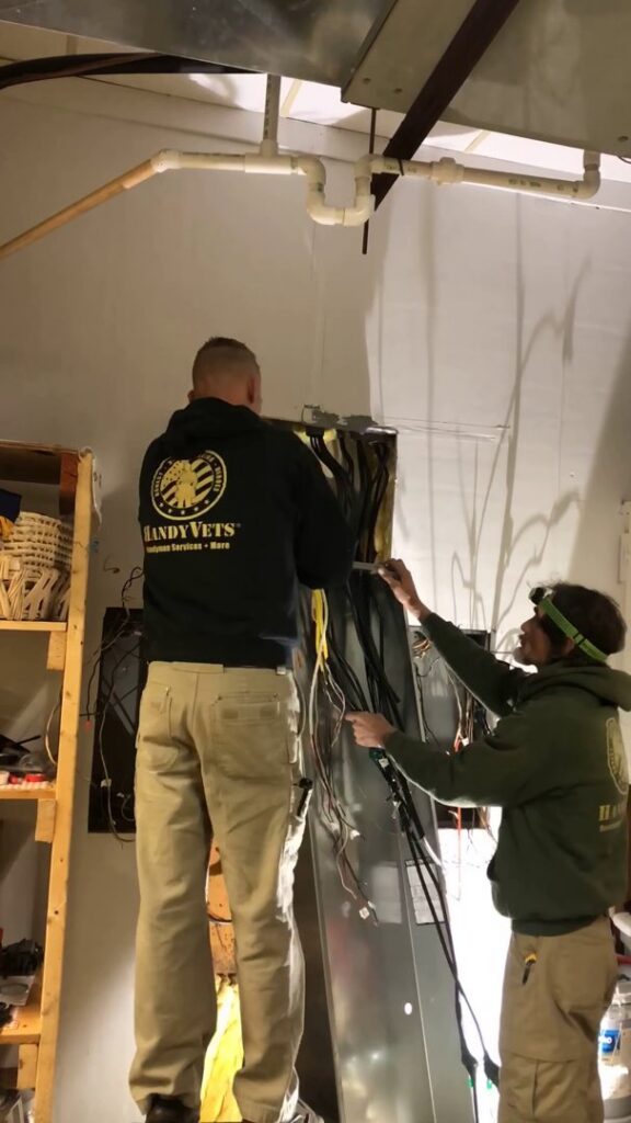 Two HandyVets technicians working on electrical wiring and HVAC systems in Saint Charles, MO.