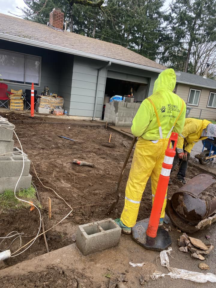 Two handymen working on site preparation and digging for a construction project by WorldWide Construction LLC in Portland, OR.