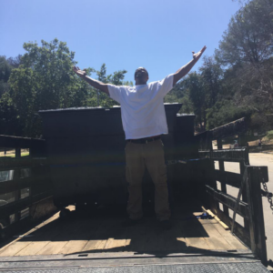 A happy team member celebrating in an empty junk removal trailer after a job for Industry Services, LLC in Inglewood, CA.