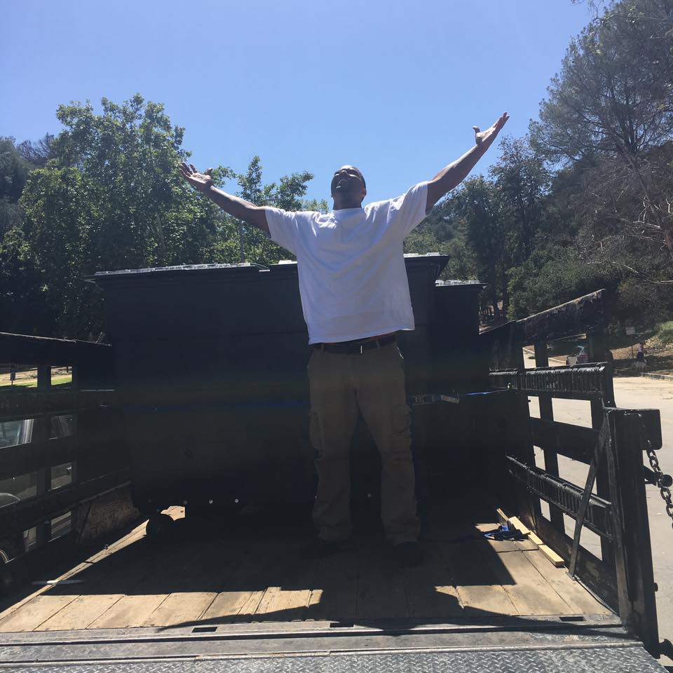 A happy team member celebrating in an empty junk removal trailer after a job for Industry Services, LLC in Inglewood, CA.