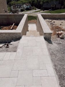 A hardscape pathway and steps under construction, featuring brick retaining walls, by Creative Pools and Hardscape in Franklin, TN.