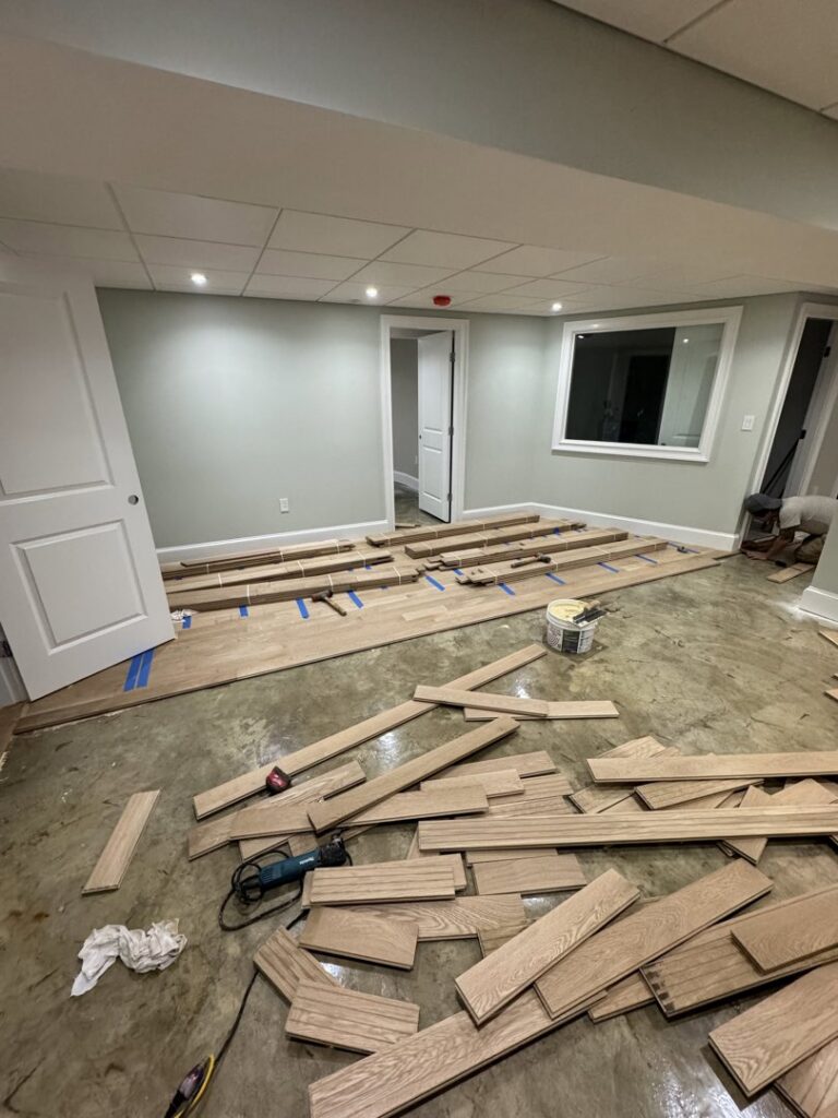 Hardwood floor installation in progress with planks and tools on a concrete subfloor by Diamond Flooring LLC in Boston, MA