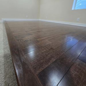 Newly installed dark hardwood flooring next to carpet by Supreme Home Improvements in Channahon, IL