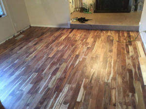 Handyman installing new hardwood flooring with tools in a home in Layton, UT by E & E Handyman Services.