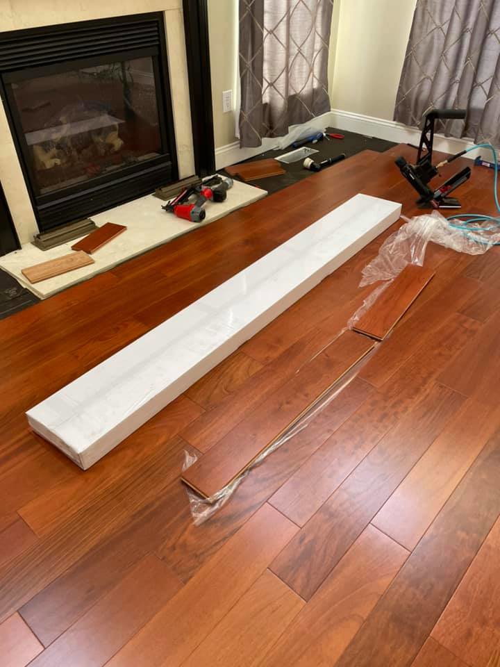 Hardwood floor installation tools and new planks near a fireplace by Just Floor It Hardwood Floors LLC in Philadelphia, PA