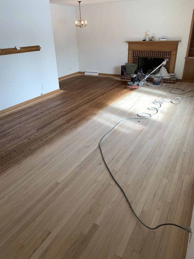 Hardwood floor refinishing in progress, showing sanding and staining by Segovia LLC interiors in Madison, WI.